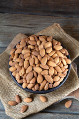 Almonds in round bowl on rustic wooden background 