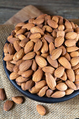 Almonds in round bowl on rustic wooden background 