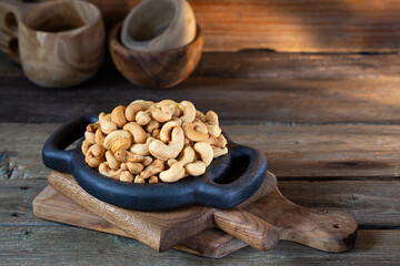 Cashew nuts in round bowl on wooden background 