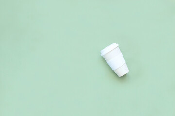 Reusable thermos - Cup beige on a green background. The concept of zero waste.