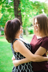 Love of mother and daughter. Aged woman and her adult daughter in the summer park.