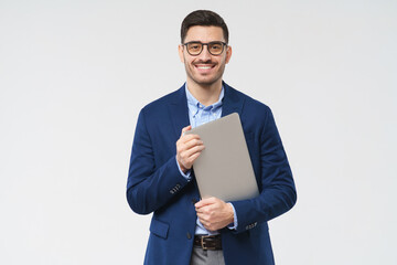 Young modern male teacher holding closed laptop in hands, waiting for students, smiling...