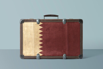 Qatar flag on old vintage leather suitcase with national concept. Retro brown luggage with copy space text.