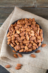 Almonds in round bowl on rustic wooden background 
