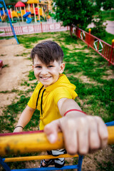 happy boy in a yellow t-shirt plays on the playground