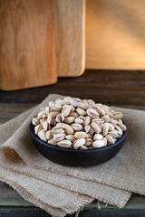 Pistachios in wooden bowl on rustic background 