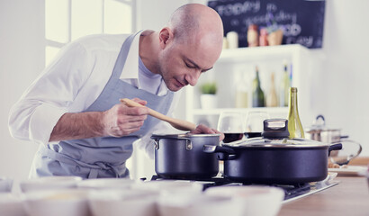 Handsome man is cooking on kitchen and smiling