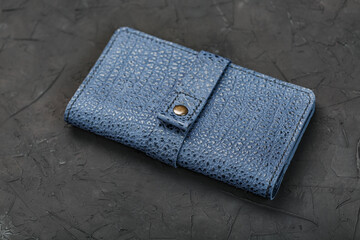 Blue leather wallet on a black textured background.