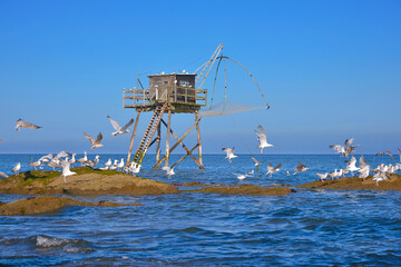 Fishing carrelet with the seagulls on the rocks at Saint-Michel-Chef-Chef in the Loire-Atlantique department in western France.