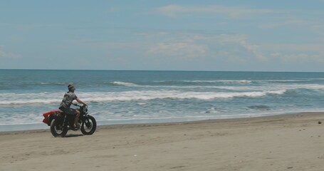 Fototapeta na wymiar Motorcyclist driving his motorbike on the beach