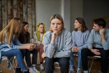 stressful caucasian female is member of alcoholics club, she want to get rid of addiction, sit apart from club and look at camera