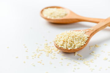 White sesame seeds in a wooden spoon on white background.
