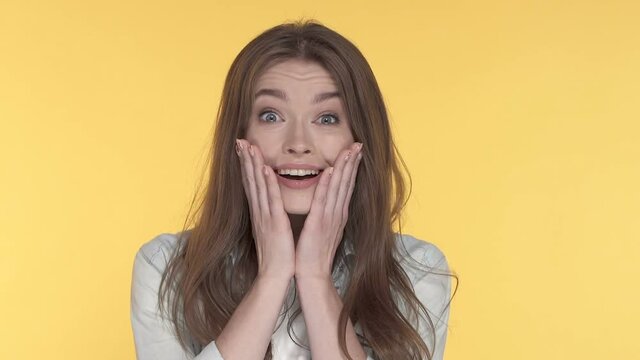 Close-up portrait of surprised woman. Slowmotion. Yellow background.