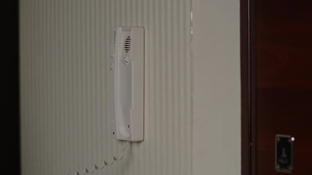 Woman answers the intercom call, pick up the phone, let the guest