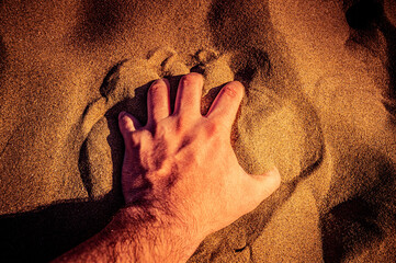 Hand of a man in the sand close up.