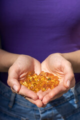 Fototapeta premium A handful of vitamin d capsules are in women's hands. Blurred background
