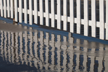 
white fence reflected in water