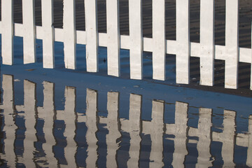 
white fence reflected in water