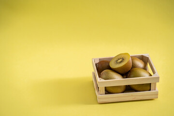 Gold kiwi in wooden fruit crate on a yellow background