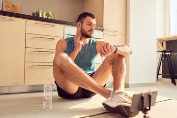 Handsome young man measuring pulse at home