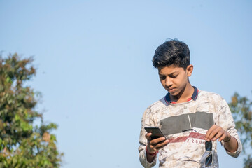teenager guy using mobile phone holding sunglasses at outdoor