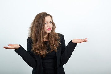 Young Attractive Woman Brunette In In A Black T-Shirt And Sweater On White Background, Confused Female Holding Hands Wide, Turned Her Palms Up. The Concept Of Frustrated, Indecisive People