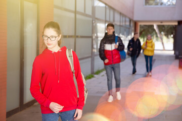 Teenage girl in red hoodie walking to college
