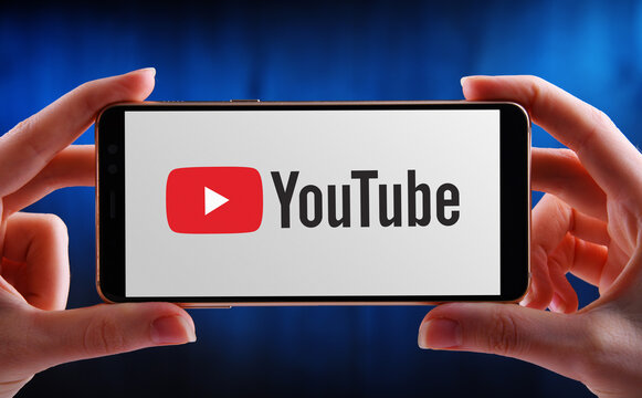 Hands holding smartphone displaying logo of YouTube