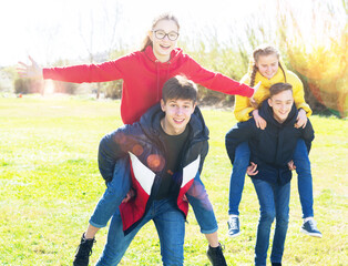 Laughing teenage girls riding piggy-back on boys