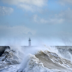 Fototapeta na wymiar Massive waves crash over harbour wall onto lighthouse during huge storm on English coastline in Newhaven, amazing images showing power of the ocean