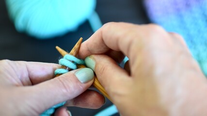 Knitting hands close up blue green wool 