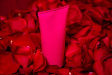 Pink tube of cream on red rose petals. The concept of a gift, eco-friendly cosmetics.