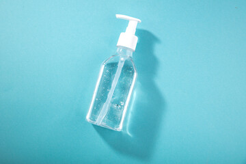 Bottle of instant antiseptic hand sanitizer transparent gel on blue background, no label....