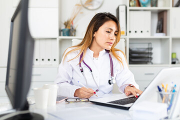 Female doctor working on laptop in office