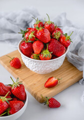 Heap of fresh strawberries in ceramic bowl on white table