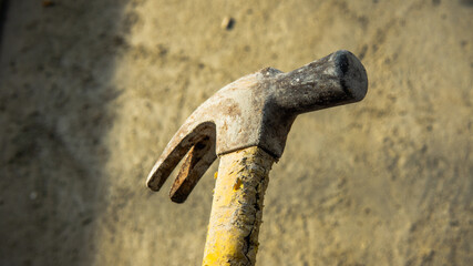 Close up view of dirty head metal hammer on grunge background with natural light and shadow. Consist of weighted head fixed to a long handle that is swung to give an impact to small area of an object.