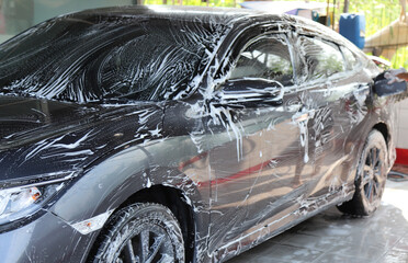 Closeup of grey car cleaning, washing after  high pressure foam spraying and rubbing by male worker.
