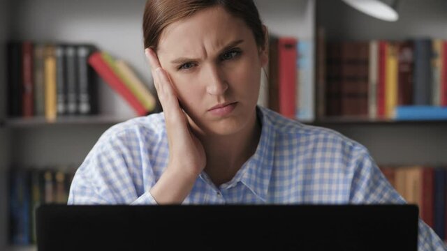 Earache. Upset young woman at workplace uses laptop, feels pain in her ear and touches his hand. Furuncle, shingles of ear, eczema concepts. Ear disease, otitis media, periodontal disease concept