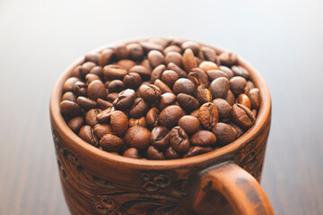 A cup filled with brown roasted coffee grains. Fragrant coffee grains.