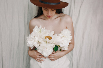 Sensual image of beautiful woman with peony bouquet instead of shirt. Fresh fragrance floral...