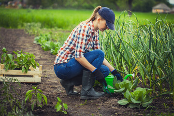 woman farmer works in a garden in a plaid shirt.