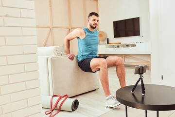 Fototapeta na wymiar Muscular young man using couch during home workout