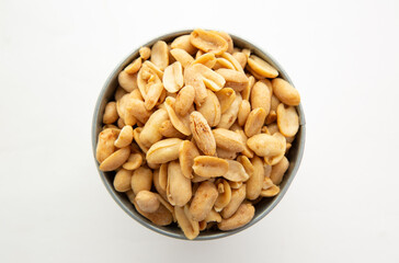 A pile of peanuts in a separate color cup on a white background top view