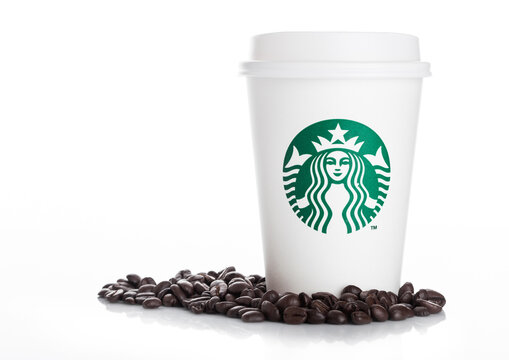 LONDON, UK - APRIL 15, 2019: Starbucks Coffee Paper Cup with fresh coffee beans on white background. Starbucks is the world's largest coffee house.