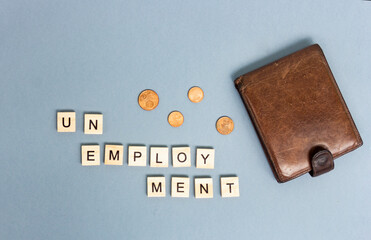 Brown wallet with scattered euro coins on a gray background. Inscription unemployment. Last money, poverty, job loss, saving concept. Flat lay, close up.