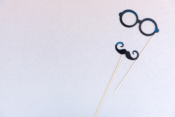 Mustache and glasses on sticks against paper. Photobooth props on a lilac  gray background.
