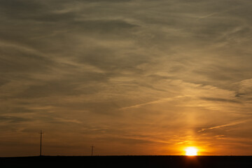 Sunset over the horizon, clouds and electric poles