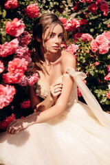 beautiful bride with blond hair in luxurious wedding dress posing in the spring garden with...