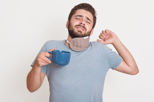 Horizontal image of tired bearded man standing isolated over white background in studio, closing eyes, raising one hand, having bad sleep, drinking coffee in morning. People and sleep concept.