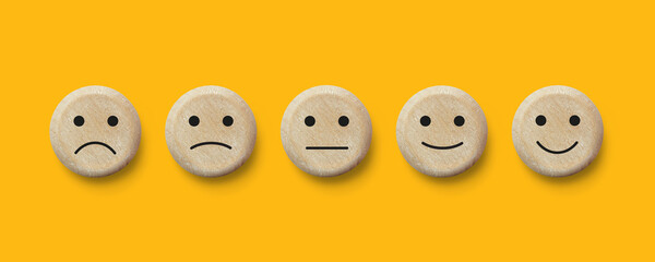 Five round wooden buttons with facial emotional expressions. Customer service evaluation and...